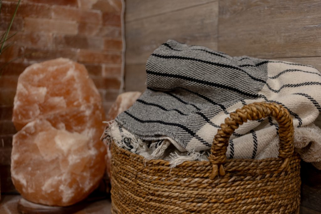 Basket of Nordic blankets beside a large salt lamp in Søle's Himalayan salt room.